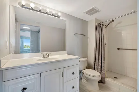 a bathroom with a sink a toilet a mirror and shower