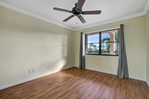 a view of empty room with wooden floor and fan