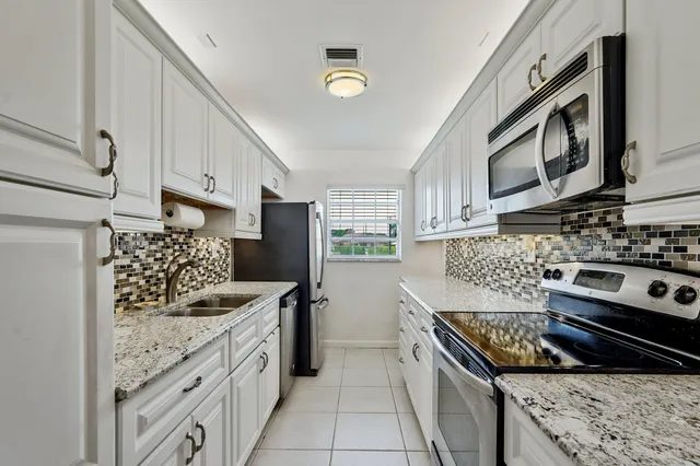 a kitchen with stainless steel appliances granite countertop a stove a sink and a refrigerator