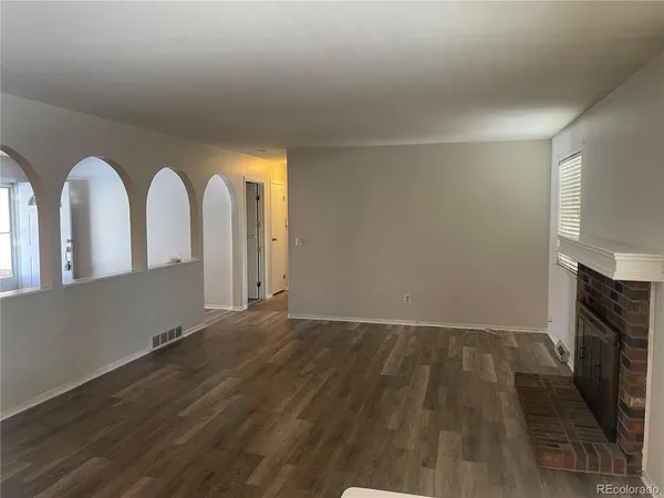 an empty room with wooden floor and a fireplace
