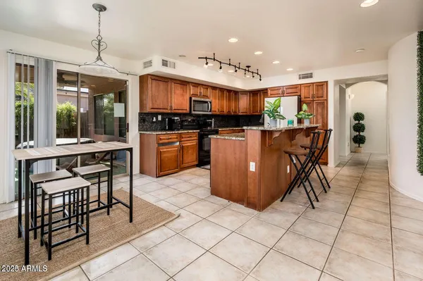 a kitchen with stainless steel appliances granite countertop a stove top oven a sink a dining table and chairs