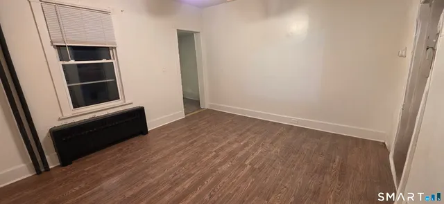 an empty room with wooden floor and entrance