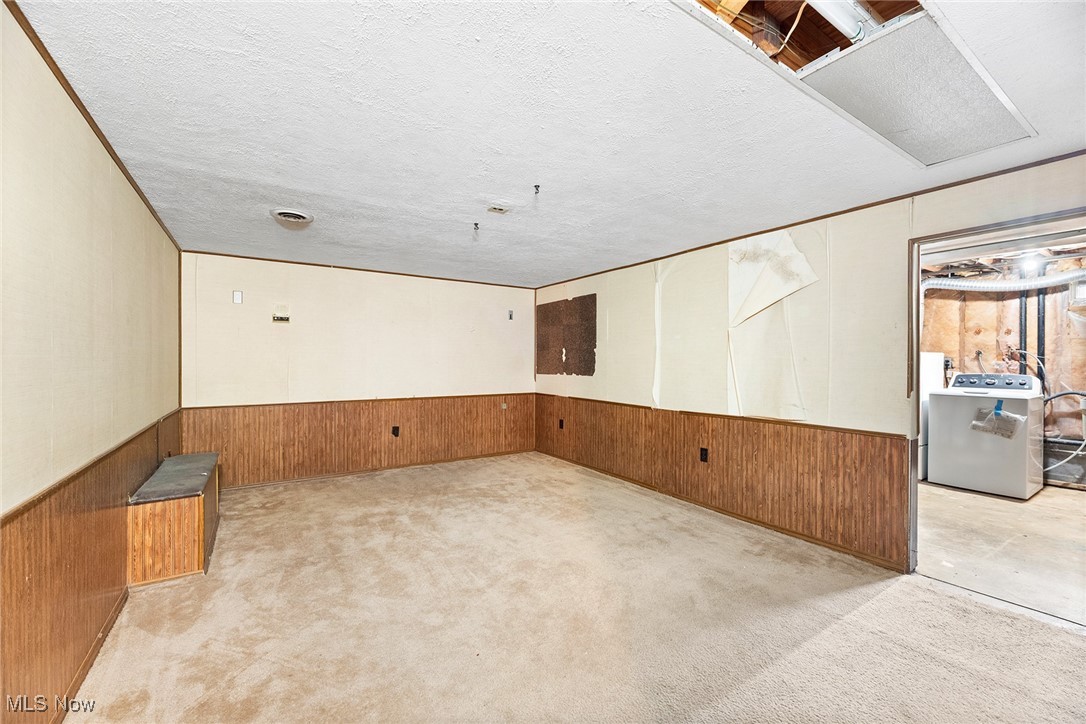 3550 Boston Road Brunswick, OH 44212 - Photo 31 of 37 Unfurnished room with wooden walls, wainscoting, washer / clothes dryer, a textured ceiling, and light colored carpet