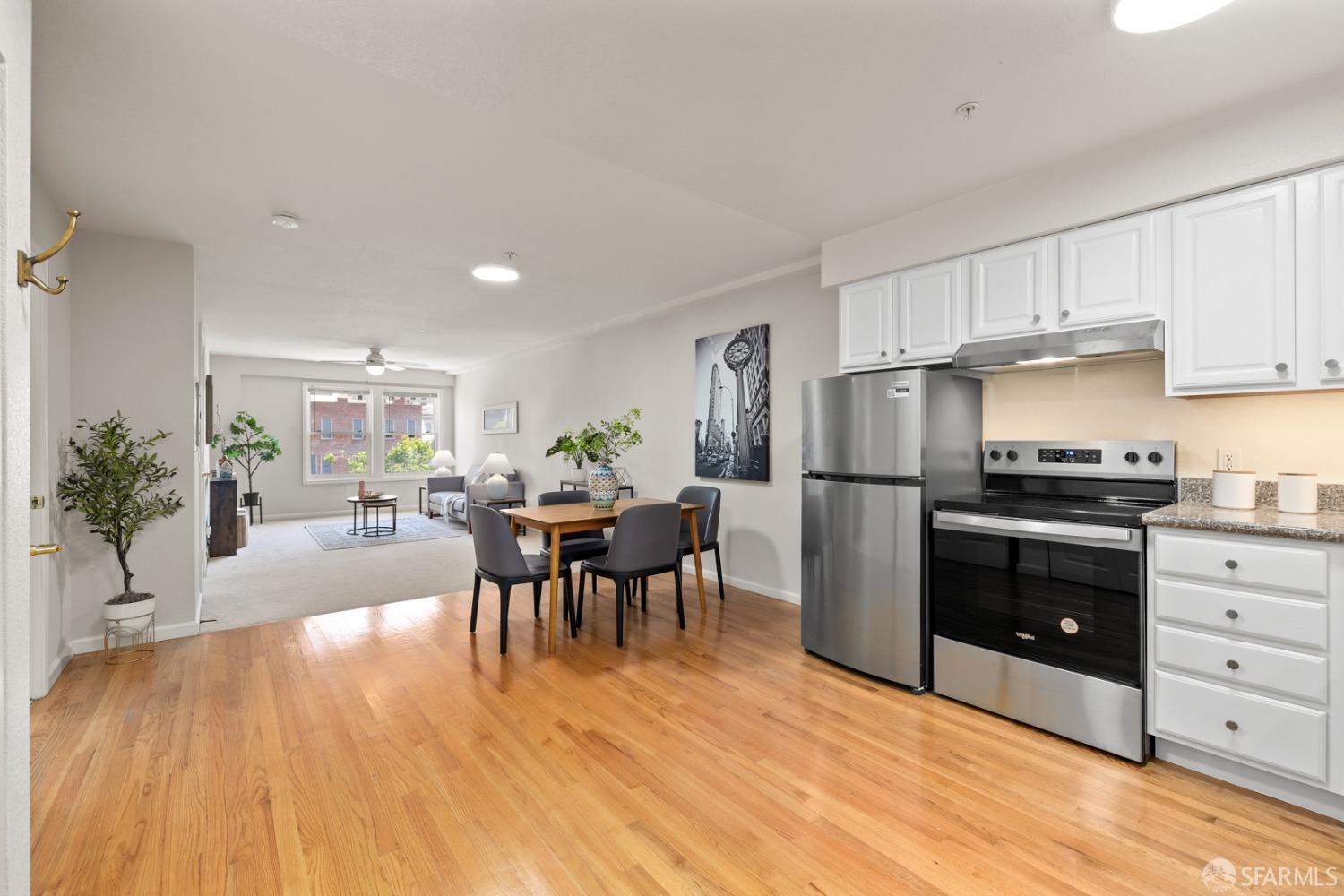 485 8th Street, Unit 402 Oakland, CA 94607 - Photo 2 of 16 a kitchen with granite countertop a refrigerator a stove a dining table and chairs with wooden floor