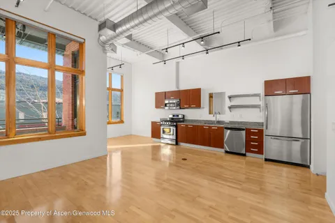 a large kitchen with stainless steel appliances kitchen island granite countertop a refrigerator and a stove top oven