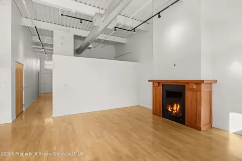 a view of an empty room with wooden floor fireplace and a window