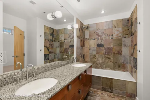 a bathroom with a granite countertop sink a toilet a mirror and shower
