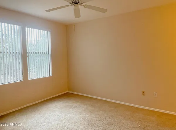an empty room with a window and a fan
