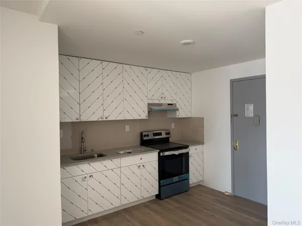 a kitchen with granite countertop a sink a stove and cabinets