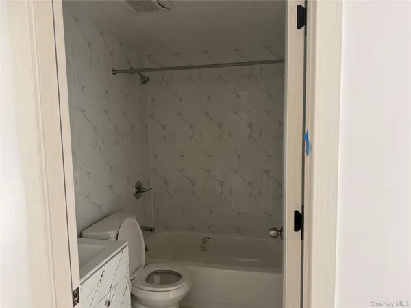 a bathroom with a granite countertop bathtub shower sink vanity and toilet
