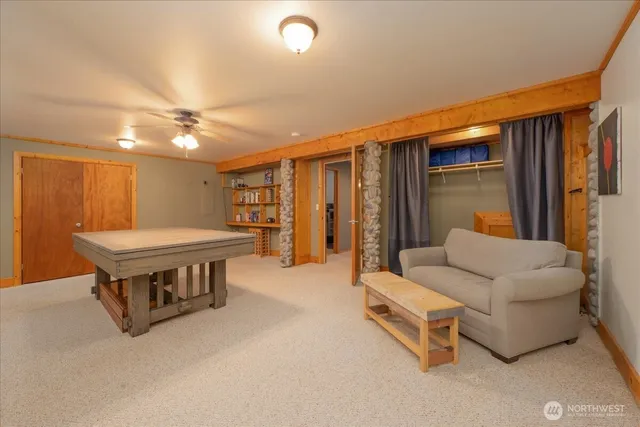 a living room with furniture pool table and a ceiling fan