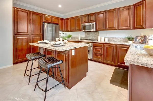 a kitchen with stainless steel appliances granite countertop a stove a sink dishwasher and a refrigerator with wooden cabinets