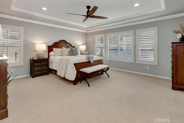 a spacious bedroom with a bed a chandelier and windows