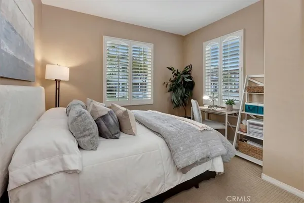 a bedroom with a bed a lamp and potted plant