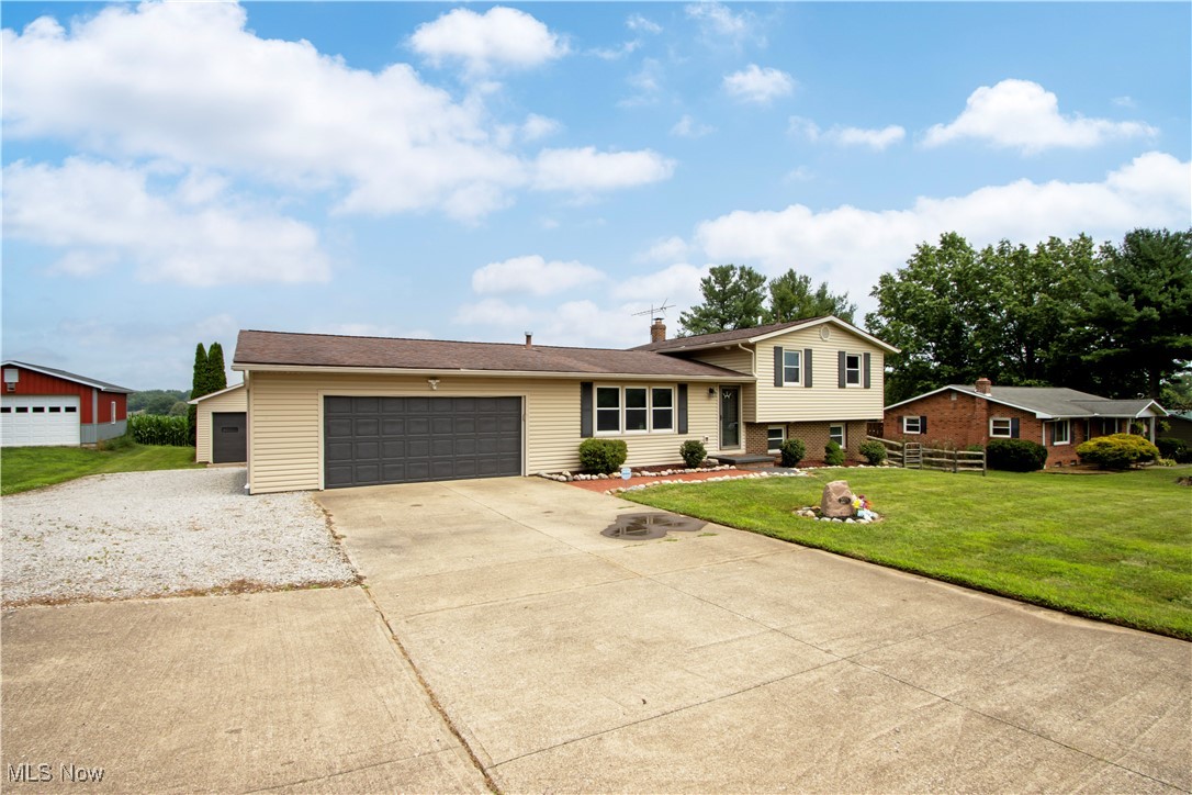 Tri-level home with driveway, a front yard, an attached garage, and a chimney
