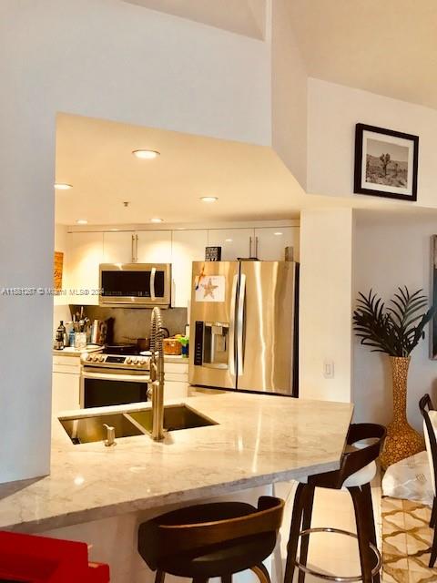 701 Brickell Key Boulevard, Unit 202 Miami, FL 33131 - Photo 3 of 27 a kitchen with stainless steel appliances kitchen island a table and chairs in it