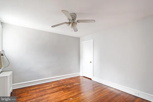 a view of empty room with wooden floor and ceiling fan