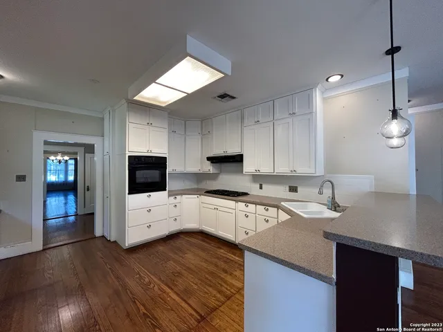 an empty room with wooden floor chandelier and windows