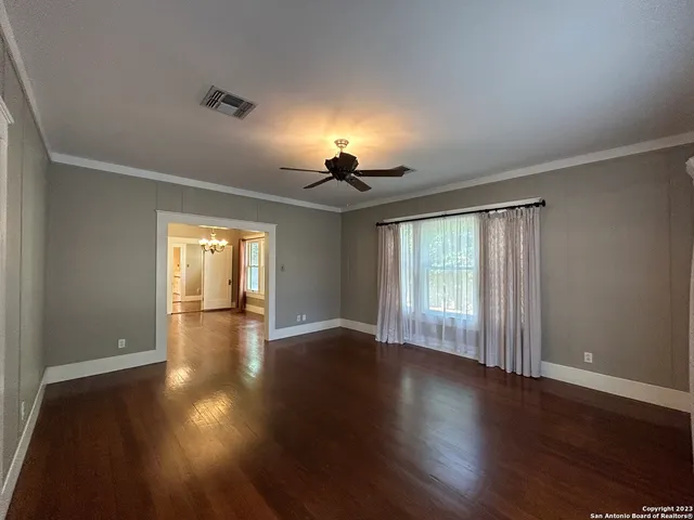 a view of empty room with wooden floor and fan