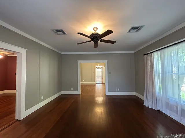 a view of an empty room with wooden floor and a window