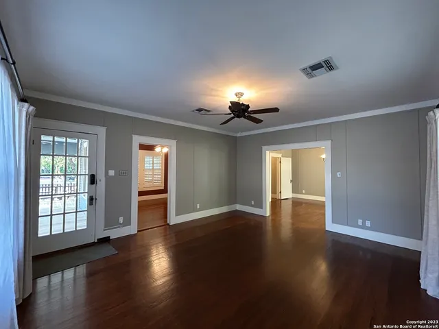 an empty room with wooden floor fan and windows