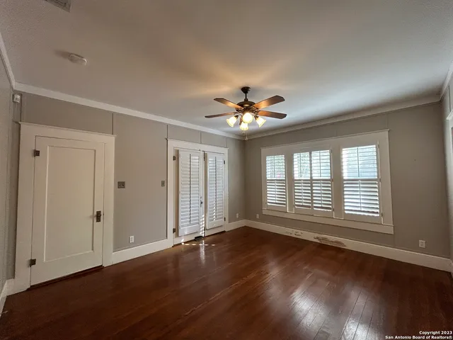 an empty room with wooden floor chandelier and windows