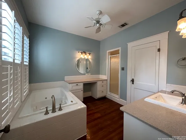 a bathroom with a tub double vanity sink and mirror