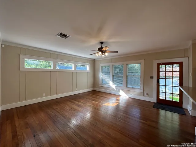 a view of empty room with wooden floor and fan