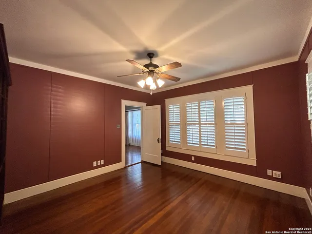 a view of an empty room with a window and wooden floor