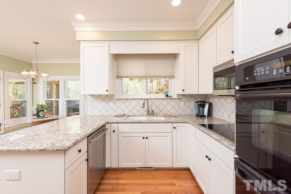 204 Reedham Way Raleigh, NC 27615 - Photo 9 of 30 Granite countertops, tile backsplash, and induction cooktop.