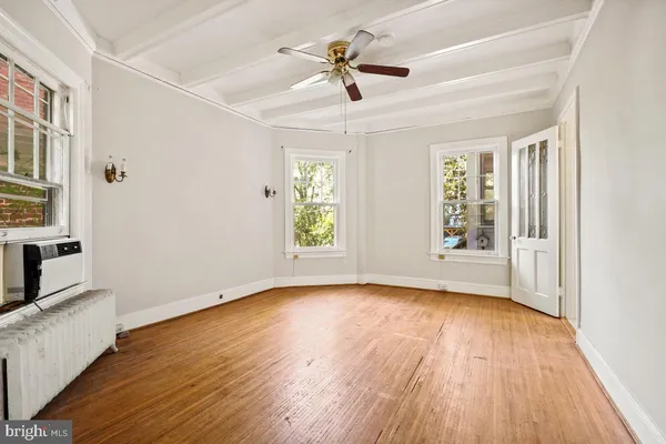 a view of an empty room with a window and wooden floor
