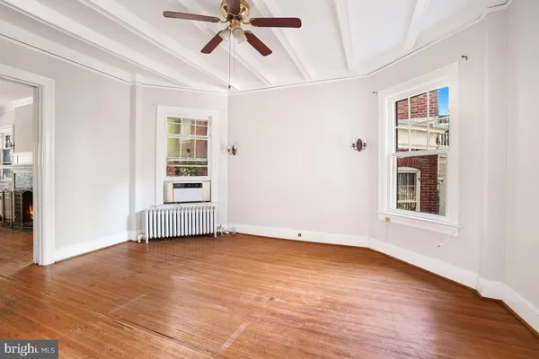 a view of an empty room with a window and wooden floor