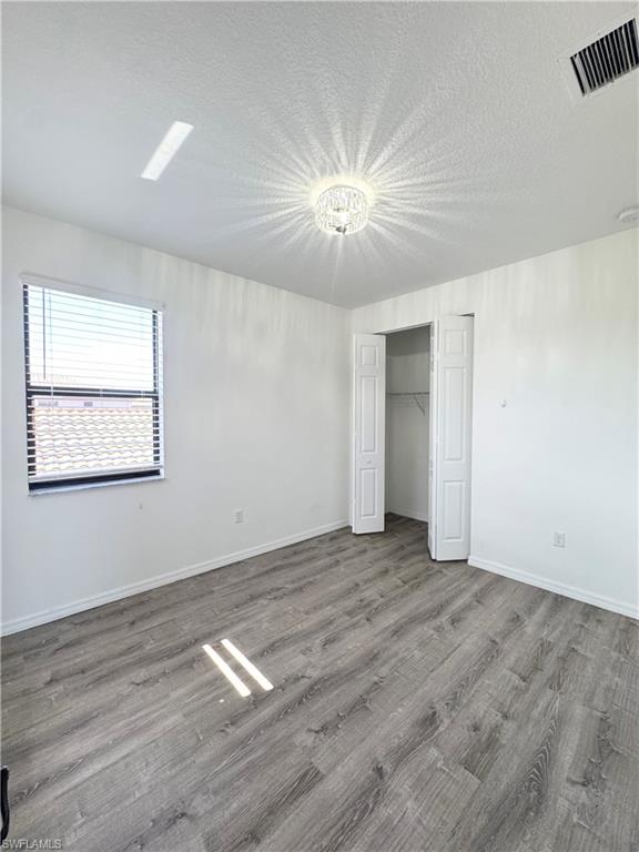 8984 Madrid Circle Naples, FL 34104 - Photo 12 of 28 a view of an empty room with wooden floor and a window