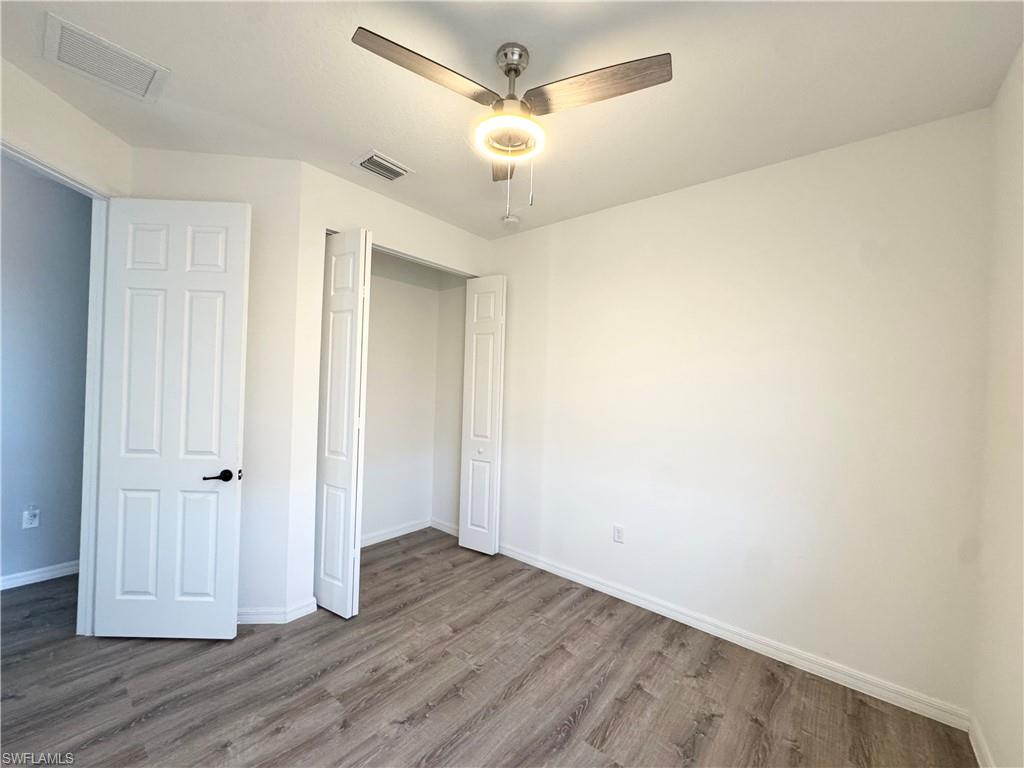 8984 Madrid Circle Naples, FL 34104 - Photo 15 of 28 an empty room with wooden floor and ceiling fan