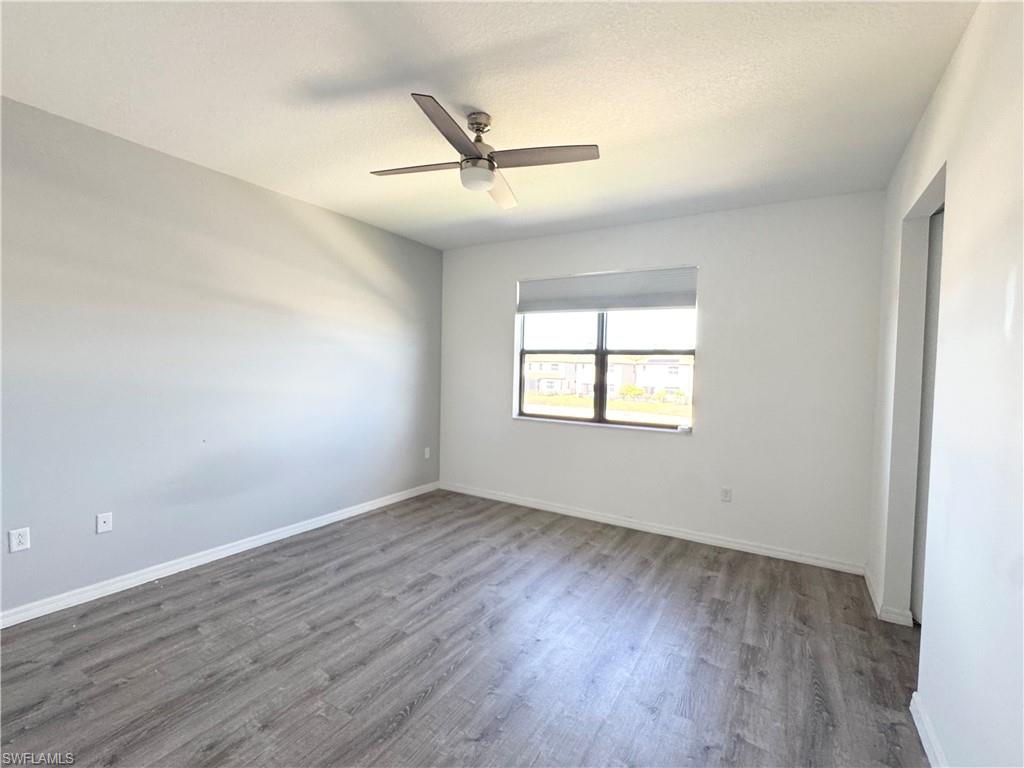 8984 Madrid Circle Naples, FL 34104 - Photo 18 of 28 an empty room with wooden floor fan and windows