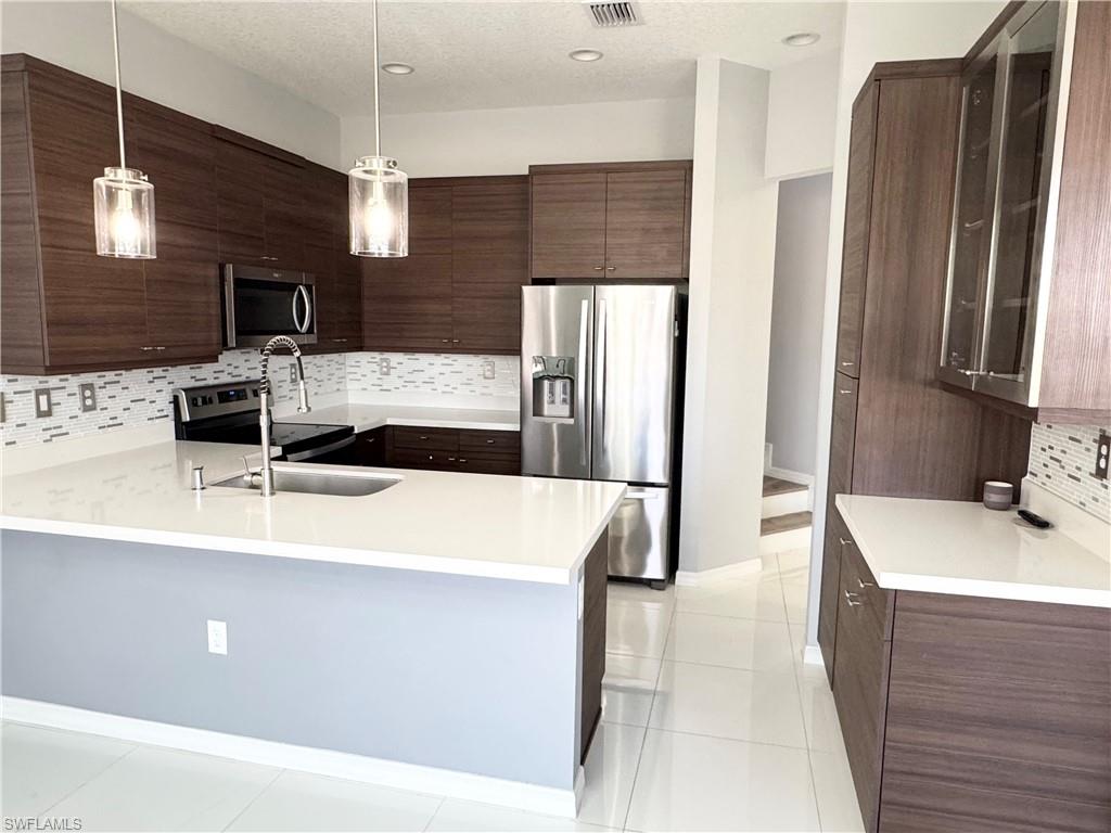 8984 Madrid Circle Naples, FL 34104 - Photo 5 of 28 a kitchen with stainless steel appliances a sink stove and refrigerator