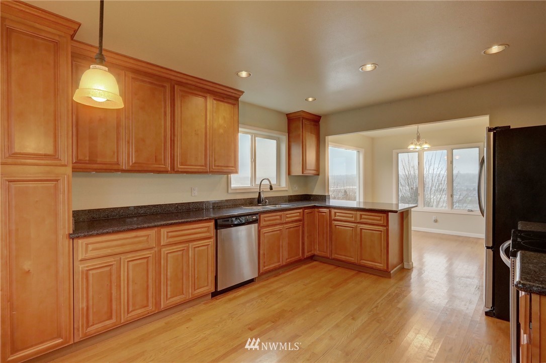 406 Stevens Avenue Northwest Renton, WA 98057 - Photo 5 of 24 a large kitchen with stainless steel appliances granite countertop a stove a sink dishwasher and a refrigerator with wooden floor