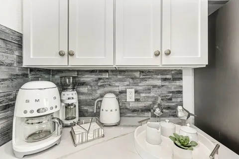 a kitchen with a sink a stove and white cabinets