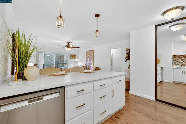 a kitchen with stainless steel appliances granite countertop a dining table chairs and white cabinets