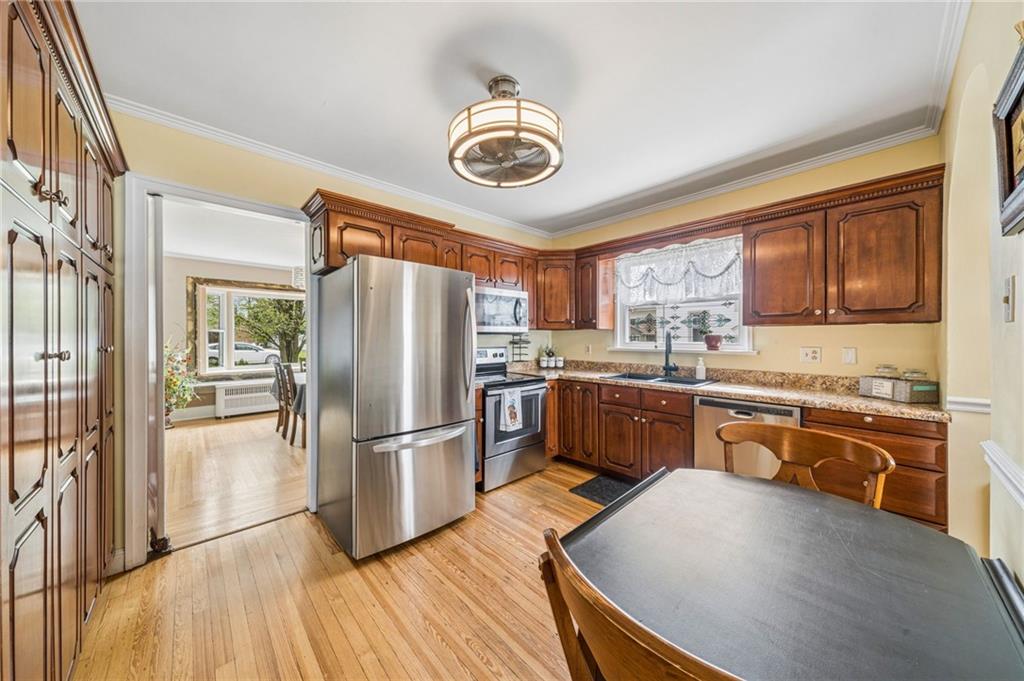 111 Orchard Avenue Rostraver Township, PA 15012 - Photo 6 of 42 a kitchen with granite countertop stainless steel appliances a stove top oven a refrigerator a sink and dishwasher with wooden floor