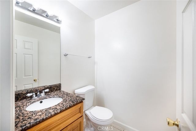 a bathroom with a granite countertop sink toilet and a mirror