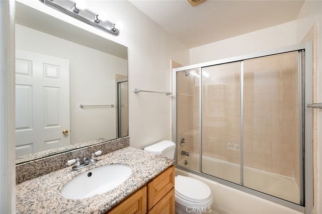 a bathroom with a granite countertop sink toilet a mirror and shower