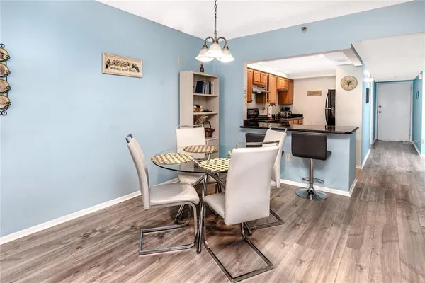 a dining room with wooden floor a chandelier a wooden table and chairs