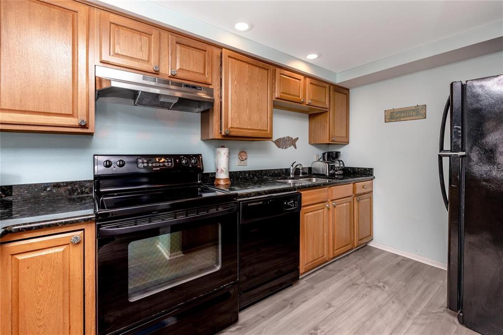 13720 Gulf Boulevard, Unit 503 Madeira Beach, FL 33708 - Photo 4 of 12 a kitchen with stainless steel appliances granite countertop a stove microwave and refrigerator