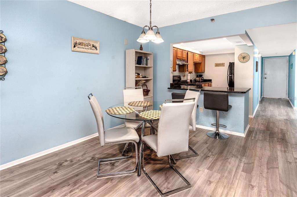 13720 Gulf Boulevard, Unit 503 Madeira Beach, FL 33708 - Photo 6 of 12 a dining room with wooden floor a chandelier a wooden table and chairs