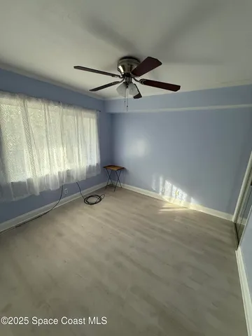 an empty room with windows and ceiling fan