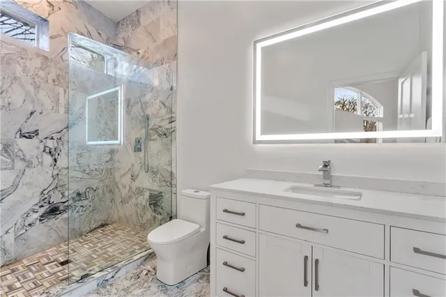 a bathroom with a granite countertop sink toilet a mirror and shower
