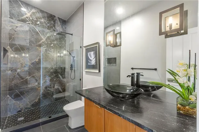 a bathroom with a granite countertop sink a toilet and shower