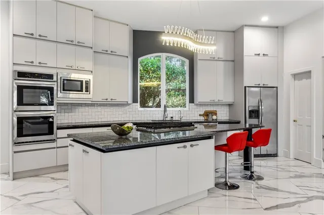 a kitchen with stainless steel appliances granite countertop a stove a sink and a refrigerator