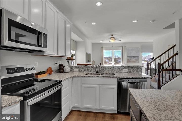 a kitchen with stainless steel appliances granite countertop a stove a microwave and wooden cabinets